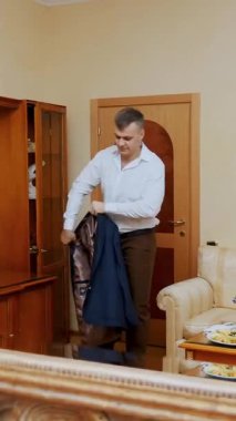 Büyük, güzel bir aynanın yansımasında genç, yakışıklı bir adam, bir iş adamı ceketini giyer ve önemli bir toplantıya hazırlanır. Damat düğün için süslenir..