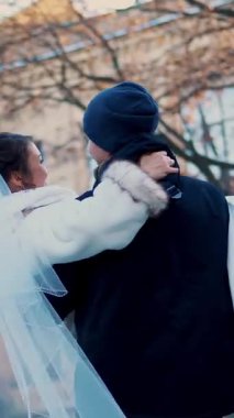 Düğün kış. Yeni evli çift gelinlik. damat gelini iplik kollarında tutar. onlar mutlular, birbirlerine gülümsüyor. Antik Mimarlık, karla kaplı park arka plan,