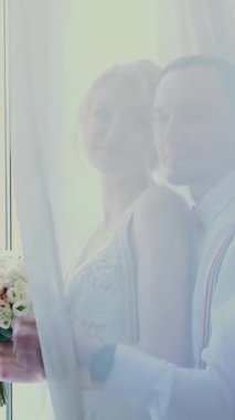 gelin ve damat perde arkasında öpücük, pencerenin yanında.