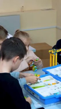 Okul çocukları, oğlanlar ve kızlar, bir tasarımcıyla çalışıyorlar, çeşitli makineler yapıyorlar, demirsiz parçalar tasarlayan robotlar, bloklar. Robot Bilimi Okulu, Kök Eğitimi