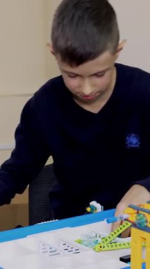 Öğrenciler, çocuklar, oğlanlar ve kızlar, talimatlara göre tasarımcı, demir olmayan parçalar, bloklar kullanarak cihazlar oluşturun. Robot Bilimi Okulu, Kök Eğitimi.