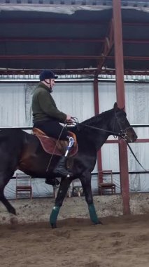 Özel hangarda bir Engelli genç hippoterapi yakın gözetim öğretmen ile bir ata binmek öğrenir. Sağ bacağı yerine yapay uzuv yaşamalı. hayvanlarla Engelli rehabilitasyonu.