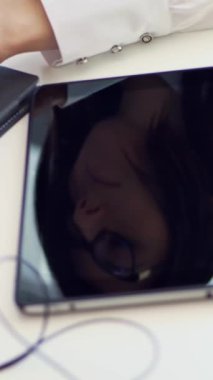 yakın çekim, bir dizüstü yanında beyaz bir masaüstü bir iş kadını gözlüklü yüz tablet ekran yansıtılır. bir şey üstünde a laptop klavye yazmakta olduğunu