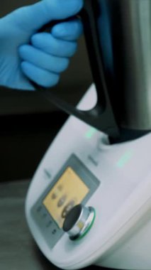 Ticari mutfak kantinde. yakın çekim, eldiven aşçı yemek için özel bir ev aleti, endüstriyel bir karıştırıcı kullanır. düğmeleri üzerinde o presler