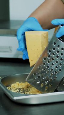 yakın çekim, eldiven aşçı peynir rende üzerinde losyonları, çanak için hazırlık yapar.