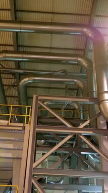 Modern bir fabrikanın içi, endüstriyel büyük hangar girişi, depo. Santral, borular, merdivenler, paneller, çeşitli teknik otomatik süreçlerin kontrol panelleri için büyük çelik yapılar.