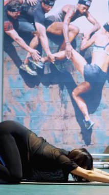 Cherkasy, Ukrayna, 20 Kasım 2019: Geniş göbekli, siyah dar eşofmanlı hamile bir kadın spor salonundaki paspasın üzerinde esneme egzersizleri yapıyor.