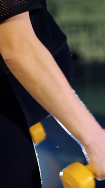 Siyah eşofmanlı, büyük göbekli genç hamile atletik kadın spor salonunda kol kasları için halterlerle egzersiz yapıyor.