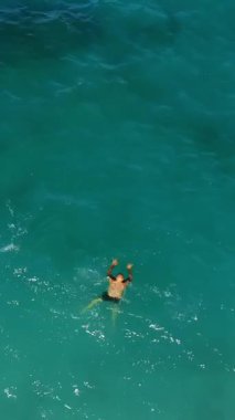 Aero, üst manzara. Turkuazda, denizin mavi sularında bir adam yüzer. Yaz sıcak güneşli gün