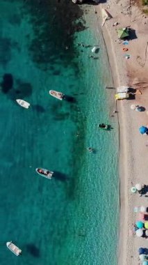 Havacılık. Üst Manzara. Güzel yaz deniz manzarası. Yunanistan 'ın Evia Adası' nın vahşi plajı. Turkuazlı deniz bölmesi, dağların eteğinde mavi su. Tatilciler plajda güneşleniyor, bir sürü şemsiye var.,