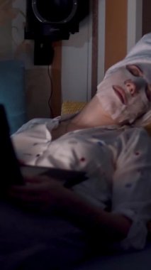 Pijamalı kız gece yatak odasında dizüstü bilgisayardan video izliyor. portre