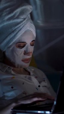 Pijamalı kız gece yatak odasında dizüstü bilgisayardan video izliyor. portre