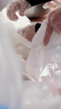 Yakın plan, eller. Gönüllüler, köpük beslenme çantalarını naylon poşetlere koyup salatalık ekliyorlar. 19. bölge boyunca fakir insanlara bedava yemek dağıtımı. Yardım projesi, bağış yardımı.