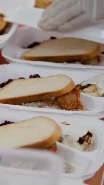 Yakın plan, Gönüllüler, kovid19 kilitlenmesi sırasında fakir insanlara ulaştırılmak üzere ücretsiz sıcak yemek paketleri hazırlıyorlar. Yemek servisi. Yardım projesi, bağış yardımı