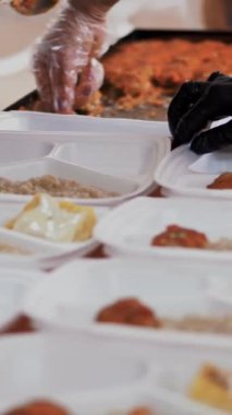 Yakın plan, tek kullanımlık eldivenler, yardım çantalarına sıcak yemek doldurur. Gönüllüler tarafından 19. koğuş boyunca fakir insanlara ücretsiz teslim edilir. Yemek servisi.