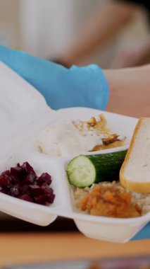 Yakın plan, eldivenli kadın elleri Covid19 hapsi sırasında zavallı, evsiz insanlar için sıcak yemek içeren köpük beslenme çantası tutuyor. Bedava yemek servisi. bağış yardımı,