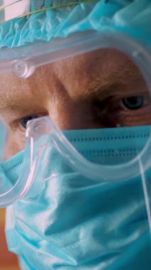 Özel koruyucu giysili, maskeli, gözlüklü ve koruyucu perdeli bir erkek doktor portresi. Yorgun ve bitkin doktor. Koronavirüs salgını