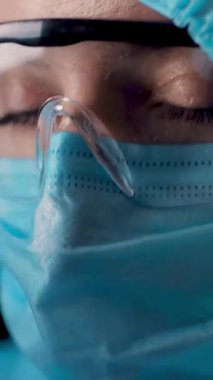 Kadın bir sağlık çalışanının portresi. Yorgun ve yorgun doktor koronavirüs koruyucu üniforma, maske, gözlük ve koruyucu ekran çıkarıyor. Bir salgın covid-19