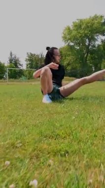 Aero, top view, spor giyimli kadın spor minder üzerinde çeşitli egzersizler yapıyor, yeşil futbol sahasında, stadyumda beyaz işaretli. Açık hava sporları. Online eğitim. Sıcak yaz günü. sağlıklı yaşam tarzı kavramı