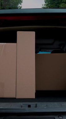 Yakın plan, erkek kurye paketleri boşaltıyor, bagajdan karton kutular, açık hava. Kargo teslimat servisi.