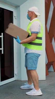 Coronavirüs salgını sırasında hastaneye tıbbi ekipmanla birlikte paket teslimatı. Kurye, koruyucu maskeli, eldivenli, doktora karton kutu veriyor, tıp uzmanı. Kargo teslimat servisi karantina sırasında.
