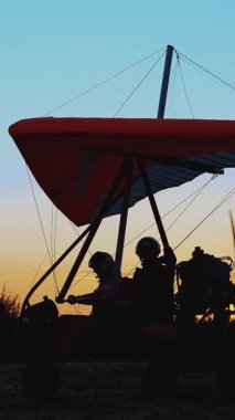 Gün batımında, motorlu planörlerin karanlık silueti yolcu ve pilotla kalkışa hazırlanıyor.