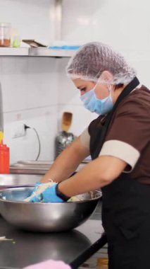 Yemek pişirmek. Şef, koruyucu maskeli ve eldivenli, büyük bir kasede salata hazırlıyor. Sağlıklı yemek. Güvenlik kavramı. Matarayı yeniden açıyorum. Gönüllülük ve yardım