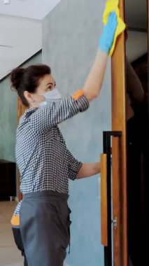 Bayan temizlikçi, koruyucu maskeli ve eldivenli, restoranda ya da kamu kuruluşunda antiseptikle kapı kollarını siliyor. Koronavirüse karşı koruma, güvenlik kavramı