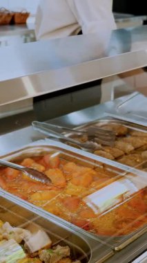 Yemek pişirmek. Yakın plan. Garson koruyucu eldivenlerle konteynırları yemeklerle, cam vitrinlerin arkasında, self servis kafeteryasında ya da açık büfede açar. Sağlıklı yemek. Gönüllü olmak ve yardım. Yeniden açılıyor. güvenlik kavramı.