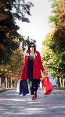 Elinde renkli alışveriş torbaları olan bir kadın, şehir sokağında yürüyor. Alışveriş ve hediyeler. dağıtım ya da bağış konsepti.