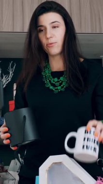 Tasarımcı hediye paketliyor. Çekici kadın dekoratör online yayın, konferans, video blogu, web sitesi, akıllı telefonun önünde duruyor. çevrimiçi çalış.