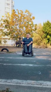 Tekerlekli sandalye. Engelli adam. Otomatik tekerlekli sandalyede engelli genç bir adam yaya geçidinden karşıya geçiyor..