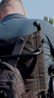 Tekerlekli sandalye. Engelli adam. Arkadan bak. Tekerlekli sandalyedeki genç adam yaya geçidinden karşıya geçiyor. Arkaplanda yeşil ışık var