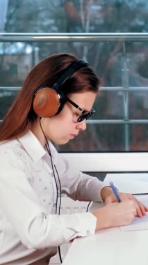 Uzaktan öğrenme, online eğitim. Liseli kız bilgisayarında öğretmeninin açıklamalarıyla çevrimiçi video dersi izliyor ve not defterine not alıyor. Evde online ders çalışıyorum..