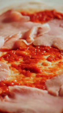 Aşçılık. Pizza yapmak. Yakın çekim, üst görüş. Şef dilimlenmiş eti pizza hamuruna koyar. Geleneksel İtalyan pizzası pişirmek. İtalyan Yemekleri.