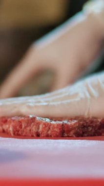 Aşçılık. Hamburger pişirmek. Yakın plan. Tek kullanımlık eldiven giyen şef kıymalı köfte yapıyor. Aşçı hamburger için sığır eti madalyonu yapar. Fast food, abur cubur.