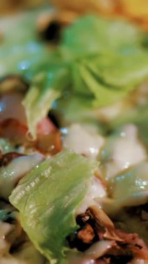 Aşçılık. Pizza yapmak. Yakın plan. Lezzetli, sulu, taze hazırlanmış, üzerinde marul yaprakları ve bitkiler olan sıcak pizza. İtalyan pizzası pişirme süreci .