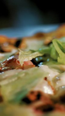 Aşçılık. Pizza yapmak. Yakın plan. Lezzetli, sulu, taze hazırlanmış, üzerinde marul yaprakları ve bitkiler olan sıcak pizza. İtalyan pizzası pişirme süreci .