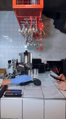 NFC teknolojisi. Garson, koruyucu maske ve eldiven takmış, parmak izleri, akıllı telefon kullanarak müşterilere ulaşılamayan ödemeler için ölümcül boyutta. Elektronik ödeme makinesi veya kart okuyucu üzerinden telefonla ödeme.