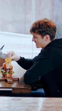 Mutlu genç adam öğle yemeğini rahat, parlak bir restoranda ya da kafede yer..