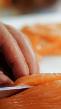Geleneksel Japon yemekleri. Suşi hazırlığı. Yakın plan. Suşi şefi taze somon filetosunu suşi barında beyaz bir kesme tahtasıyla doğruyor. Suşi nigiri balığı hazırlıyorum. Japon mutfak tarifleri..