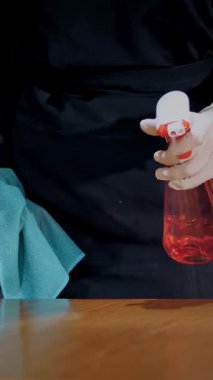 Yakın plan, koruyucu eldivenli bir garson, antiseptik sprey ve temizlik peçetesi kullanarak restoran masalarını siler. pandemik koronavirüs.