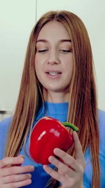 Sağlıklı bir yaşam tarzı. Sağlıklı yemek. Online beslenme uzmanı. Güzel bir kadın evdeki mutfakta akıllı telefonuyla video çekiyor. Kameranın karşısına geçip sağlıklı beslenmeden bahsediyor..