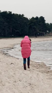 Kışın deniz kenarında yürümek. Hüzünlü, yalnız bir kadın, paltosuyla, kumlu sahilde yürüyor deniz ya da nehir dalgaları arasında, rüzgarlı, soğuk ve bulutlu bir kış gününde. Arkadan bak. Kışın sahil boyunca yürü.