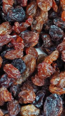 Kuru üzüm. Yakın plan. Rotasyon yemeği. Üzüm arka planı yavaş döner, üst görünüm. Sağlıklı beslenme için kuru meyve, hafif ve koyu kuru üzüm. Yemek geçmişi. Gastronomi konsepti, organik gıda..
