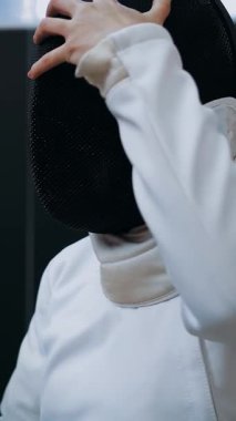 Engelli atlet. Eskrim. Felç oyunları. Tekerlekli sandalye çiti. Beyaz eskrim üniformalı engelli kadın eskrimci portresi antrenmandan önce siyah eskrim kaskı takıyor..