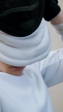 Engelli atlet. Eskrim. Felç oyunları. Tekerlekli sandalye çiti. Beyaz eskrim üniformalı engelli erkek eskrimci portresi antrenmandan önce siyah eskrim kaskı takıyor..