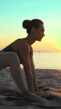 Açık havada uzanıyor. Yoga silueti. Yoga kumsalı. Atletik genç kadın gün batımında ya da gün doğumunda plajda yoga yapıyor. Spor salonu açık havada. Sabahları spor yapıyorum..