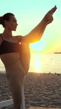 Barre. Açık havada uzanıyor. Yoga kumsalı. Bale antrenmanı. Atletik genç kadın gün batımında ya da gün doğumunda plajda egzersiz yapıyor. Spor salonu açık havada. Fitness, bale, spor