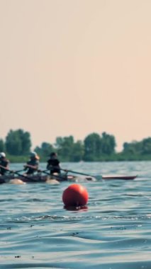 Kürek yarışması. İnsanlar kano yapıyor. Kürek çeken kürek çeken insanlar güneşli bir yaz gününde sakin bir nehir boyunca yelken açıyorlar.